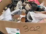 une boîte en carton remplie de chaussures posée par terre