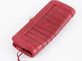 portefeuille en cuir rouge avec une étiquette attachée dessus, posé sur une surface blanche