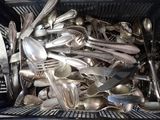 pile of silver spoons and forks in a black container