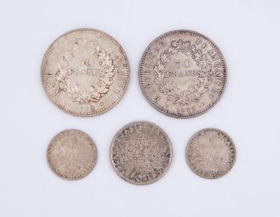 a group of five silver coins on a white surface