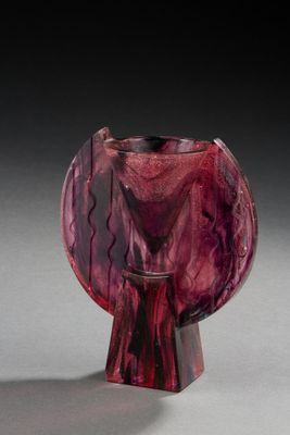 un vase en verre violet posé sur une table, devant un fond noir