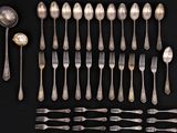 a lot of silver spoons and forks on a black table