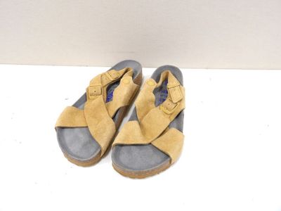 pair of yellow sandals on a white surface with a white wall in the background