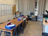 des tables et des chaises dans une salle de classe avec un tableau blanc accroché au mur