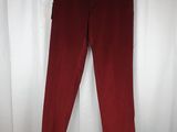 a pair of red pants hanging on a hanger in front of a white curtain