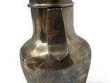 a silver vase with a metal lid on a white surface
