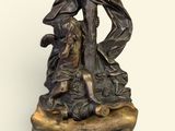 statue en bronze représentant Jésus portant la croix, assis sur un rocher en compagnie d'un chien