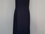 a black dress on a mannequin stand against a gray wall