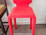 une chaise rouge placée à côté d'un tabouret de bar