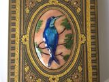 un oiseau bleu perché sur une branche d'arbre dans une boîte décorative