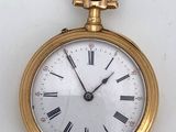 a gold pocket watch with roman numerals on the face