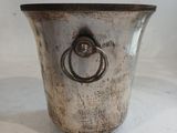 un vase en argent orné d'un anneau, posé sur une surface blanche