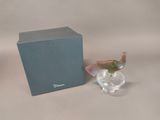 a small glass bird that is sitting next to a blue box