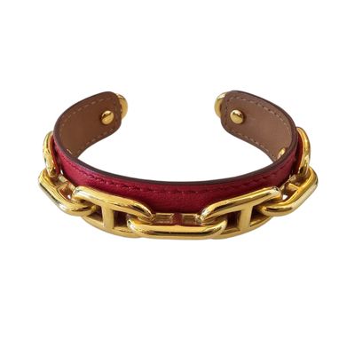 a close up of a red leather bracelet with gold chains