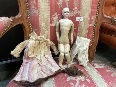 une poupée assise sur une chaise à côté d'une autre chaise