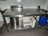 une table en acier inoxydable sur laquelle se trouvent deux seaux et une poubelle
