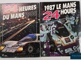 two books on a table with a picture of a race car in the background