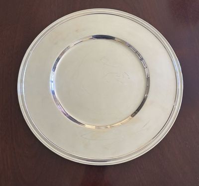 une assiette blanche bordée d'argent posée sur une table en bois