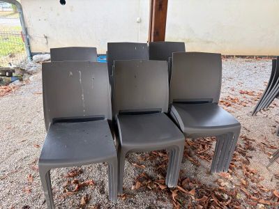 quatre chaises en plastique grises posées sur un sol recouvert de gravier