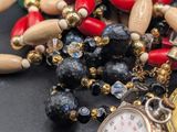 many different colored beads and a watch on a table
