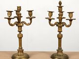 une paire de candélabres anciens en laiton avec des bougeoirs, posés sur une table
