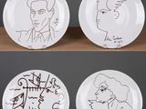 trois assiettes ornées de dessins représentant des personnes, posées sur une table