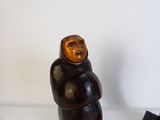 une figurine représentant un homme assis sur une table, à côté d'une paire de chaussures