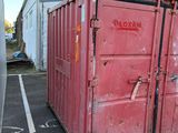 a red container sitting in the middle of a parking lot