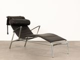 un fauteuil et un repose-pieds en cuir noir dans une pièce blanche