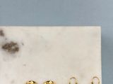 un lot de cinq boucles d'oreilles en anneau dorées posées sur une plaque de marbre
