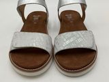 a close up of a pair of silver sandals on a white surface