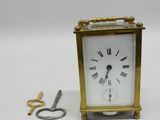 une petite horloge posée à côté d'une paire de ciseaux