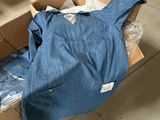 une boîte contenant une chemise bleue, posée par terre