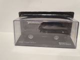 a black toy truck in a clear box on a white surface