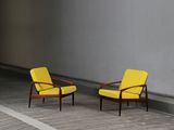two yellow chairs sitting on a wooden floor next to a white wall