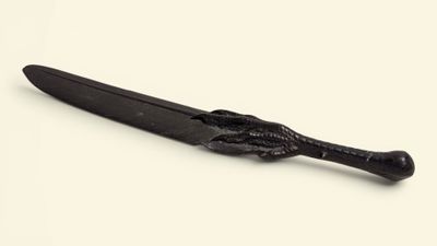 un couteau noir avec un manche noir posé sur une surface blanche
