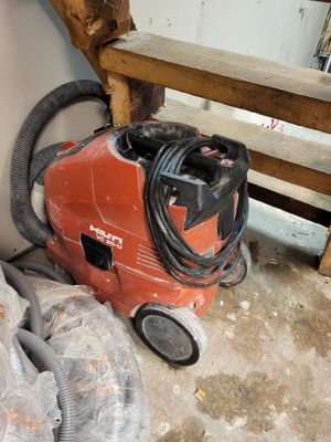 un aspirateur rouge posé par terre à côté d'un tas d'ordures