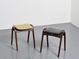 pair of stools in a room with a white wall and grey floor