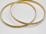 two gold bang bracelets on a white background
