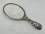 silver plated magnifying mirror on white surface with white background