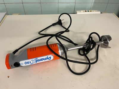 une petite perceuse électrique posée sur un plan de travail, avec son cordon d'alimentation