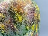 un vase recouvert d'une épaisse couche de peinture verte et jaune