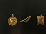 trois pendentifs en or et émeraude sur un fond noir