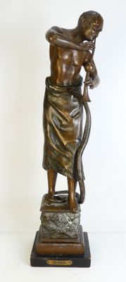 statue en bronze représentant un homme tenant un serpent, posée sur un socle en marbre