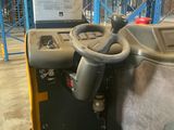 a forklift in a warehouse with shelves and pallets in the background