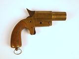 un revolver en laiton muni d'un porte-clés, posé sur une surface blanche