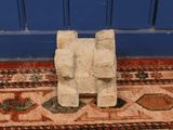 an image of a sculpture on a rug in front of a blue door