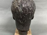 sculpture of a man ' s head on a wooden base