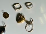 many different rings and pendants on a white surface