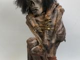 une image représentant une statue d'un squelette assis sur un tabouret